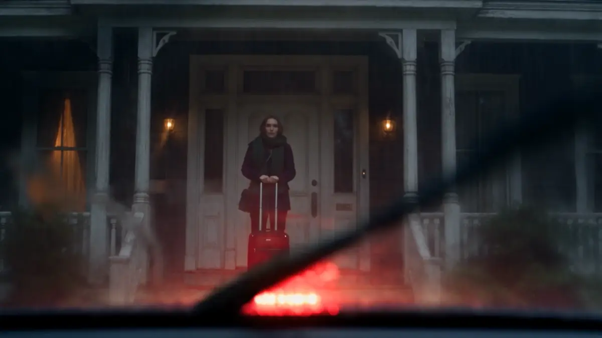 A girl with a red suitcase on a porch at dusk