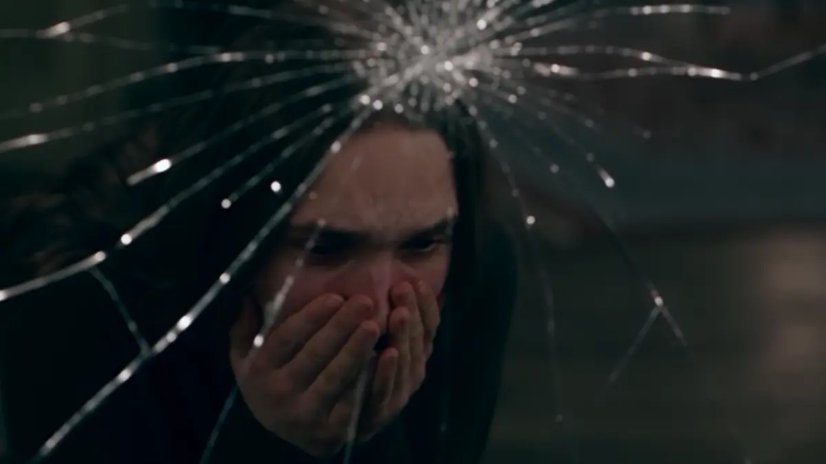 A girl crying behind cracked glass