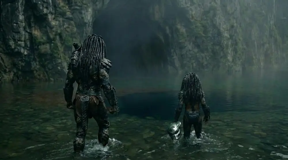 An adult and a young hunter wading toward a cave